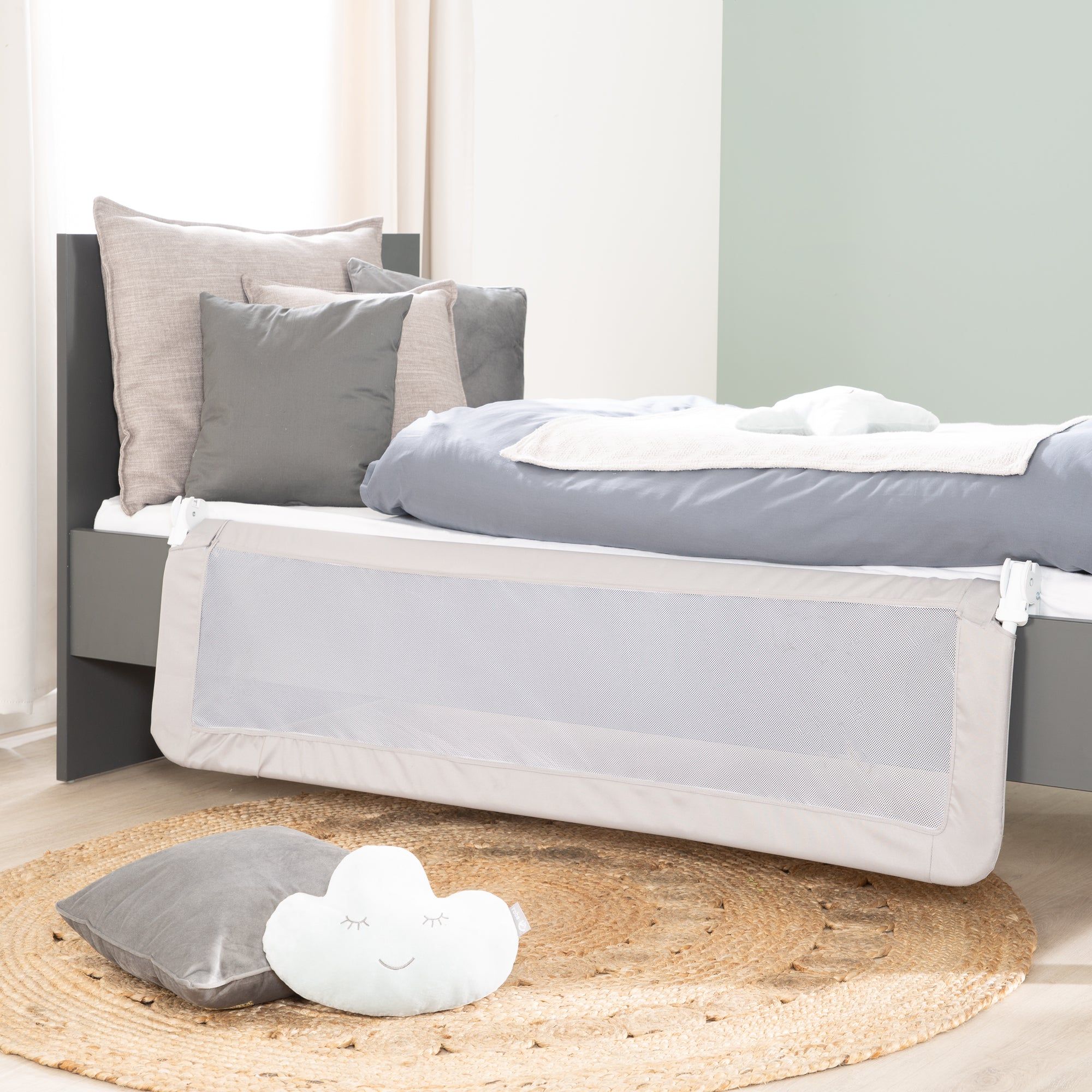 Bettgitter, weißes Netz, grauer Rahmen, am Bett befestigt. Kissen und Decke auf dem Bett.