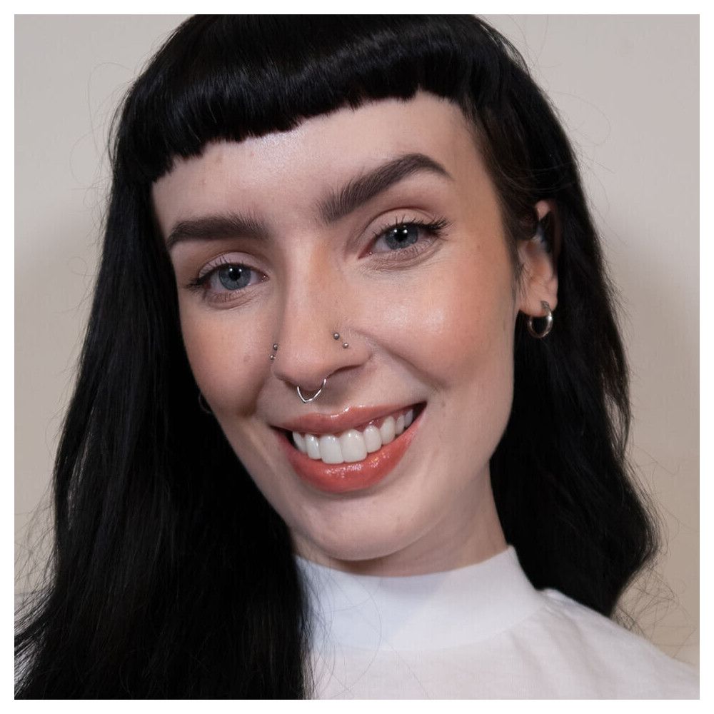 Porträt einer Frau mit Make-up. Sie lächelt. Helle Haut, dunkles Haar, Augenbrauen, Lippenstift.