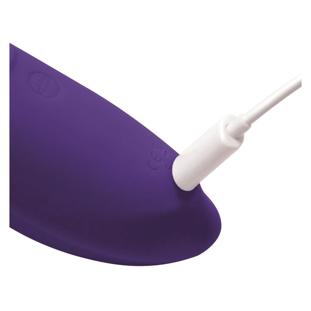 Nahaufnahme eines lila Vibrators mit einem weißen Ladekabel, das in den Vibrator eingesteckt ist.