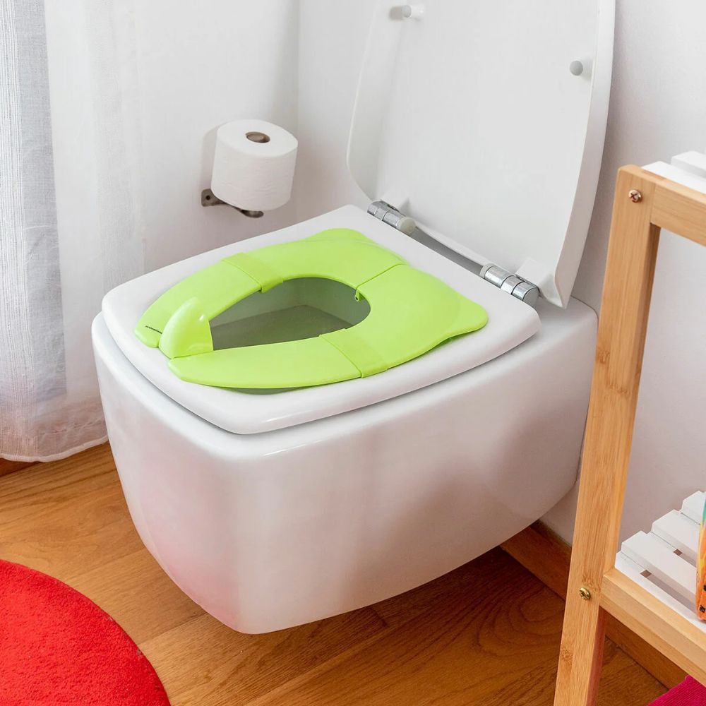 Grüner Toilettensitz für Kinder auf einer Toilette. In Badezimmerumgebung. Marke InnovaGoods.