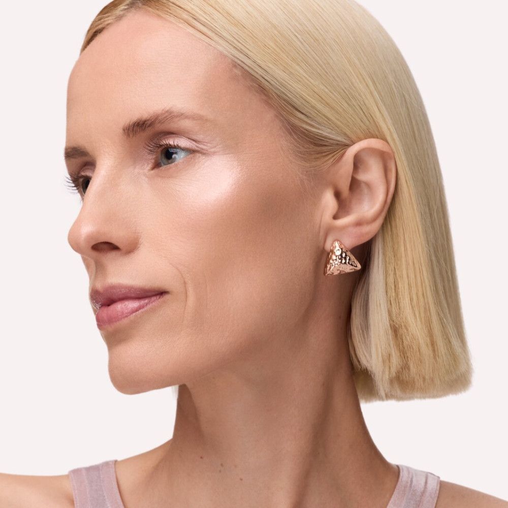 Porträt einer Frau mit blonden Haaren. Highlighter auf Wangenknochen. Goldene Ohrringe.