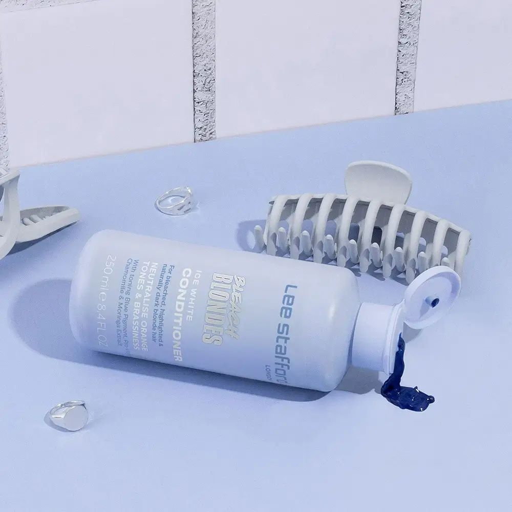 Lee Stafford Bleach Blondes Conditioner Flasche liegt auf der Seite, daneben Haarklammern.