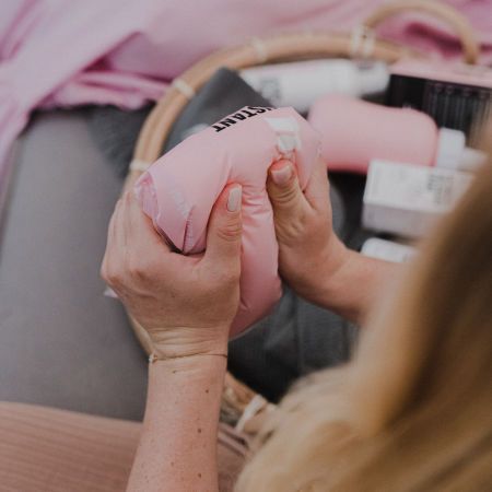 Hände halten eine gefaltete, rosa Kühlbinde. Aufschrift: "INSTANT".