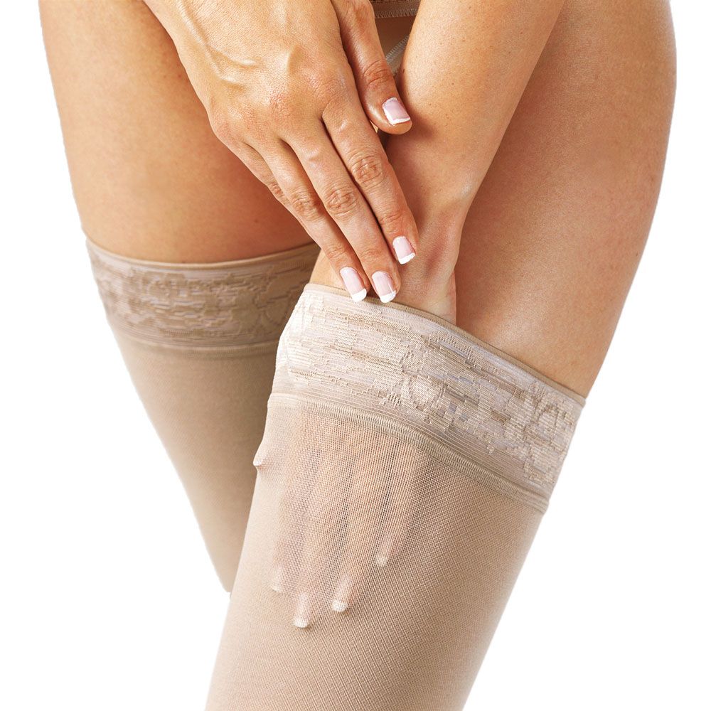 Nahaufnahme von Händen, die haut farbene Kompressions-Schenkelstrümpfe halten. Der obere Teil der Strümpfe ist sichtbar.