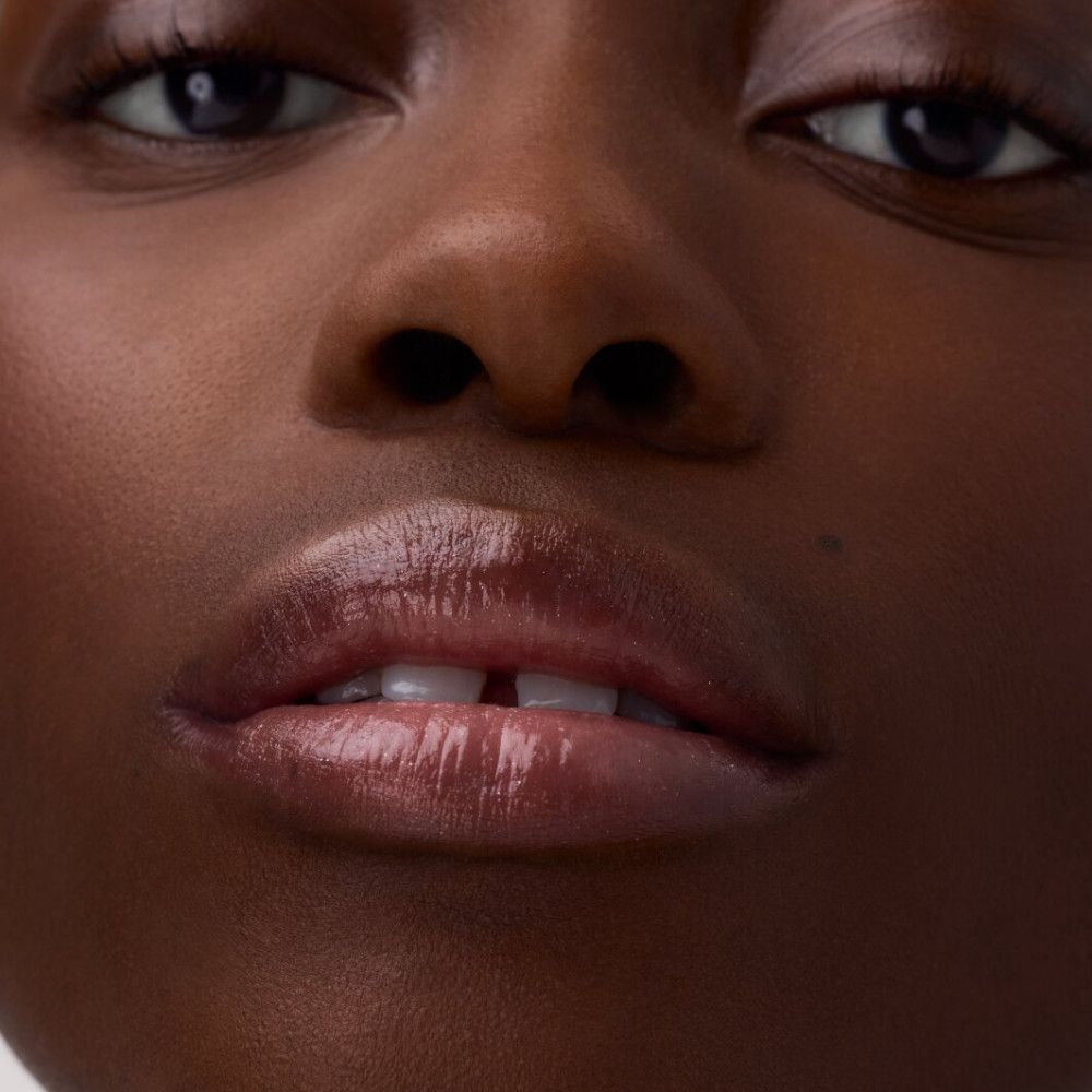 Nahaufnahme von Lippen mit aufgetragenem Lippenbalsam. Glänzendes Finish.