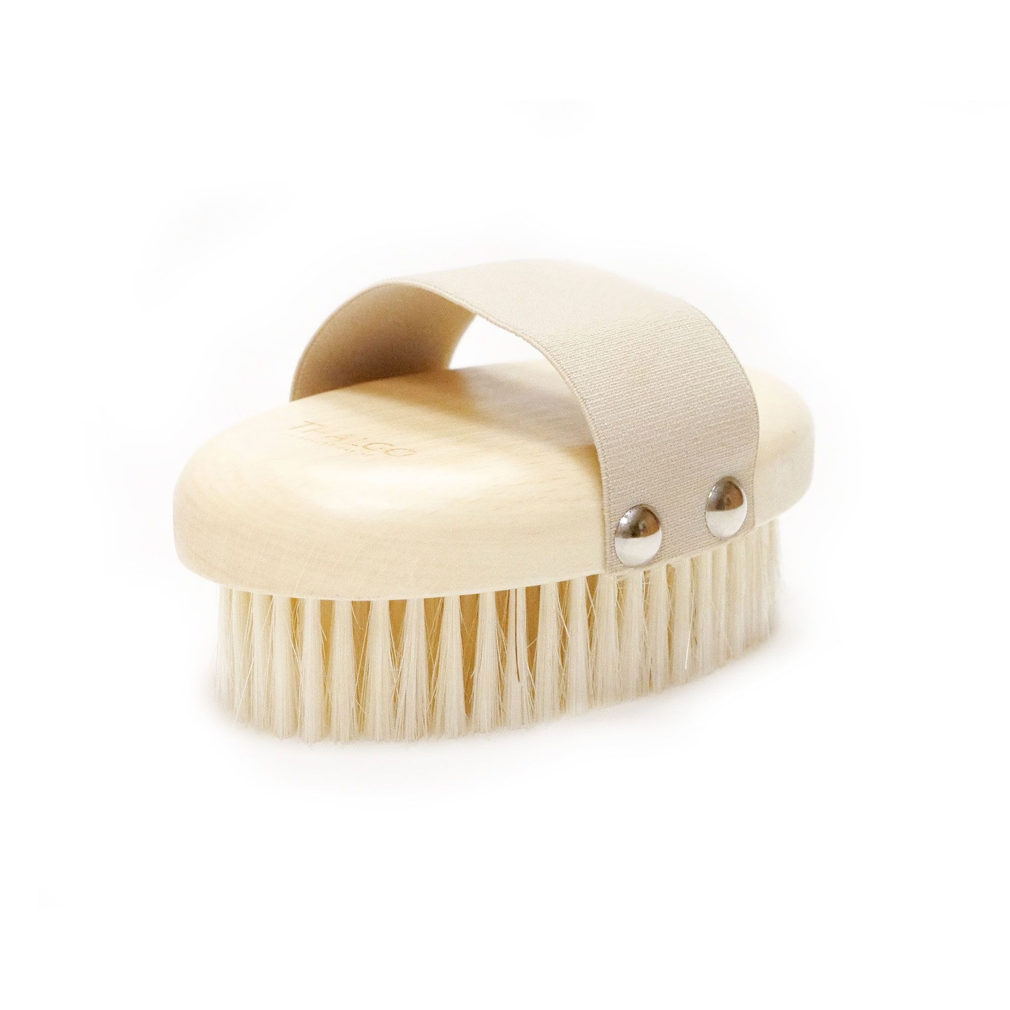 Ovalförmige Massagebürste mit hellem Holzgriff und hellen Borsten. Mit Lederband und Metallnieten befestigt.