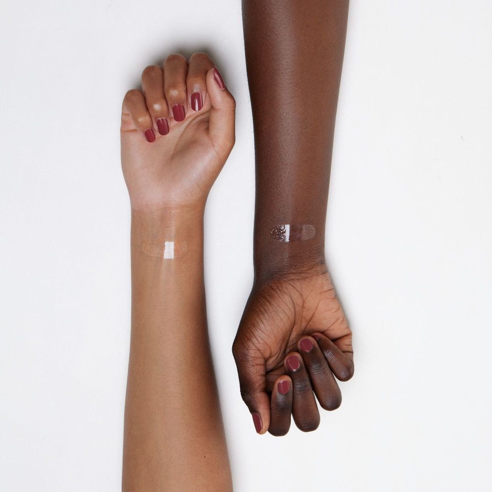 Zwei Arme mit unterschiedlichen Hauttönen. Auf den Handgelenken ist Lipgloss aufgetragen. Sichtbar: transparente Textur.