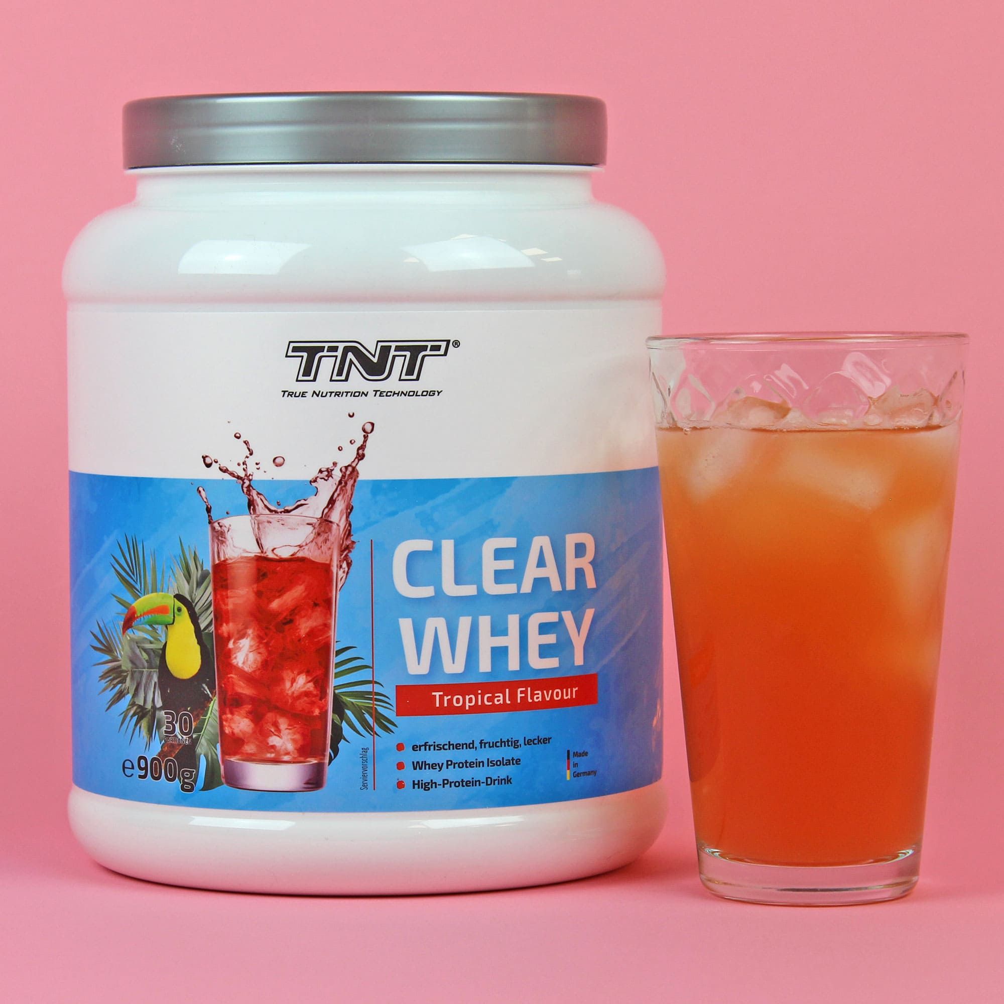 TNT Clear Whey Dose und Glas mit Getränk. Rosa Hintergrund. Dose mit Abbildung eines Getränks und Tukan.