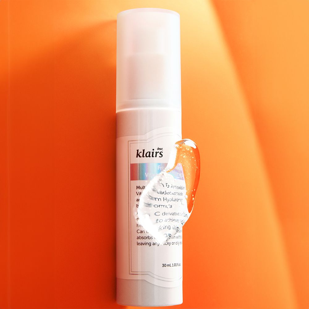 Weißes Serum-Fläschchen mit Sprühkopf. Tropfen Serum an der Seite. Aufschrift: klairs. Hintergrund: orange.