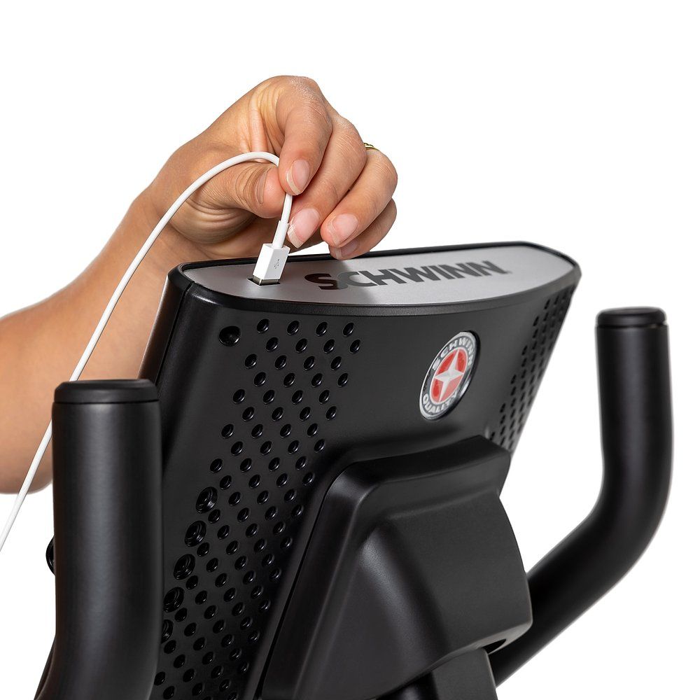 Fahrradtrainer-Konsole. Hand steckt Kabel in Anschluss. Schwinn-Logo.