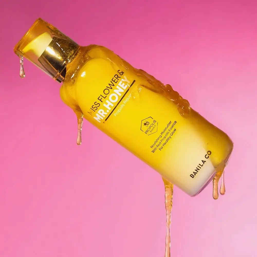 Gelbe Flasche mit honigfarbener Flüssigkeit, "MISS FLOWER & MR. HONEY" und "BANILA CO" Aufschrift.