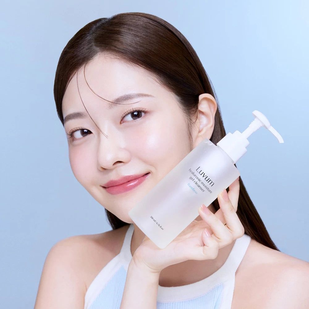 Frau hält eine transparente Flasche mit weißem Pumpverschluss. Auf der Flasche steht "Luvum Hyaluronic moisture gel cleanser".
