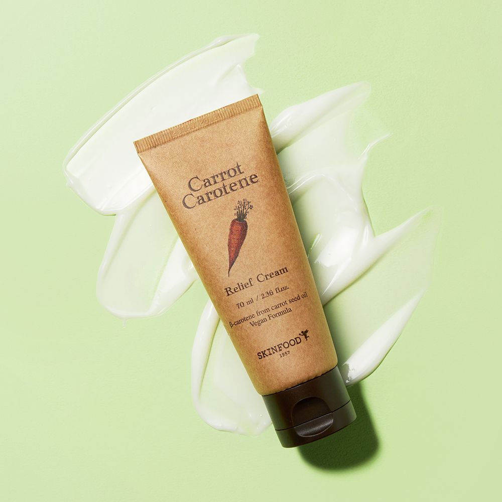 Beige Tube mit braunem Deckel auf grünem Hintergrund mit Creme. Aufschrift: Carrot Carotene, Relief Cream, SKINFOOD.