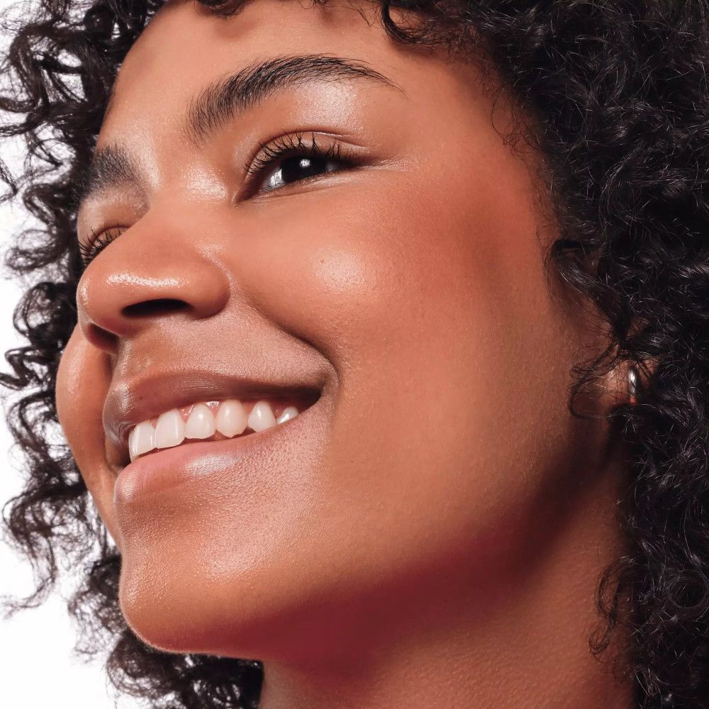 Nahaufnahme einer Frau mit gebräunter Haut. Rouge auf den Wangen. Lockiges Haar.