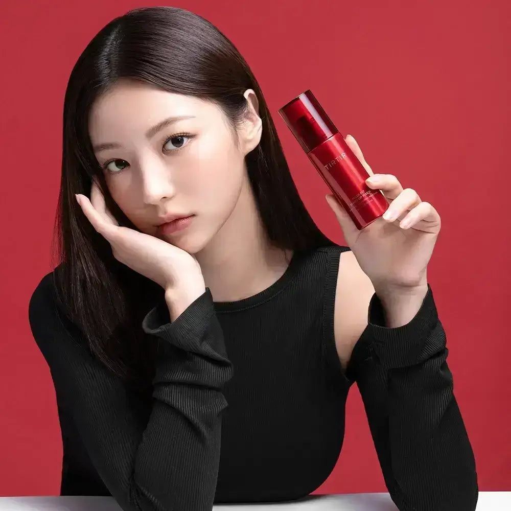 Frau hält rote Sprühflasche. Aufschrift TIRTIR, Mask Fit Make Up Fixer. Roter Hintergrund.