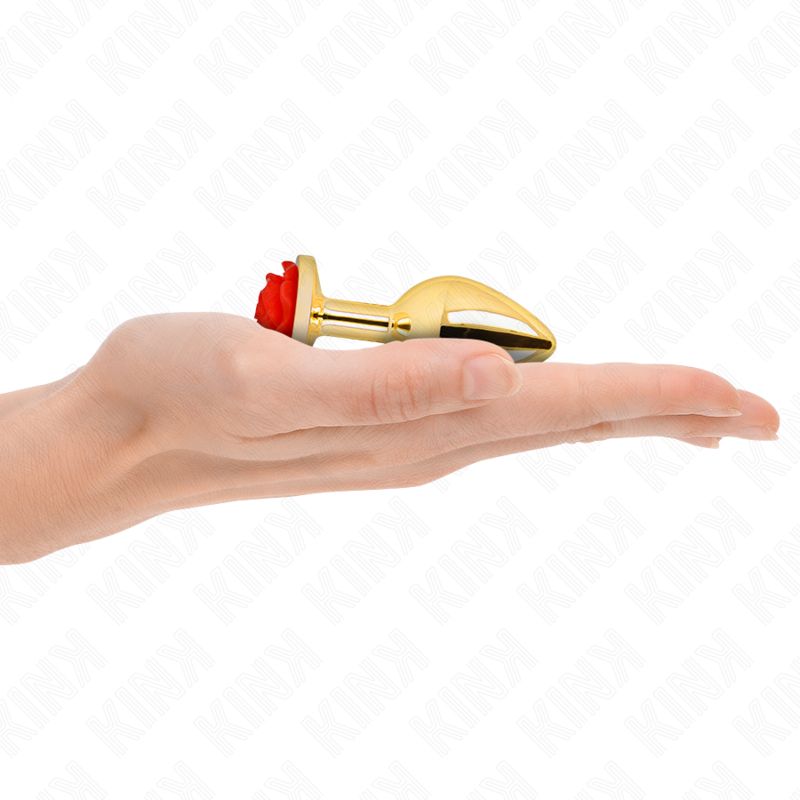 Goldfarbener Analplug mit roter Rosenbasis, in einer Hand gehalten.