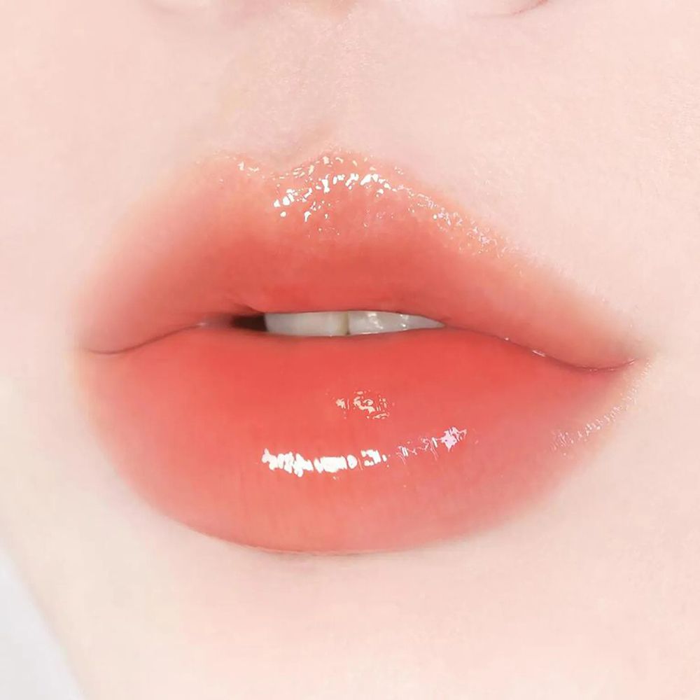 Nahaufnahme von Lippen, die mit einem glänzenden, roten Lippenbalsam bedeckt sind. Die Lippen sind leicht geöffnet.