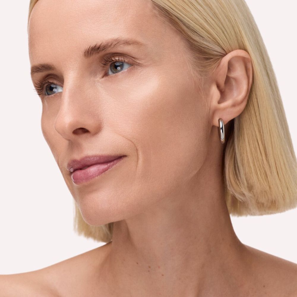 Porträt einer Frau mit blonden Haaren. Sie trägt Ohrringe. Ihr Gesicht ist mit getönter Feuchtigkeitspflege behandelt.