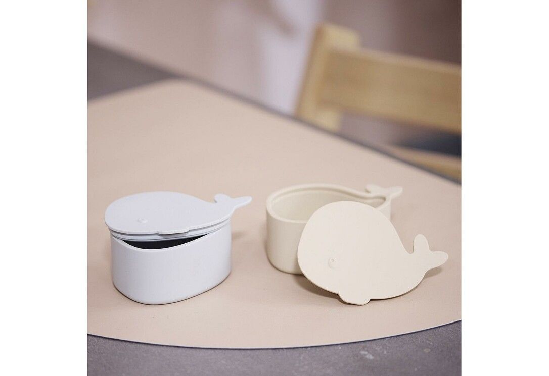 Zwei walförmige Brotdosen auf einer Tischoberfläche. Eine Dose geöffnet, eine mit Deckel.