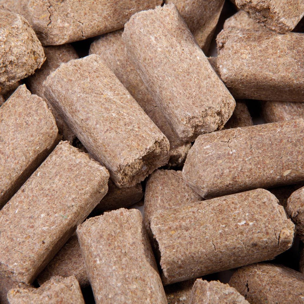 Nahaufnahme von mehreren braunen, zylindrischen Mineral-Leckerlis für Pferde.