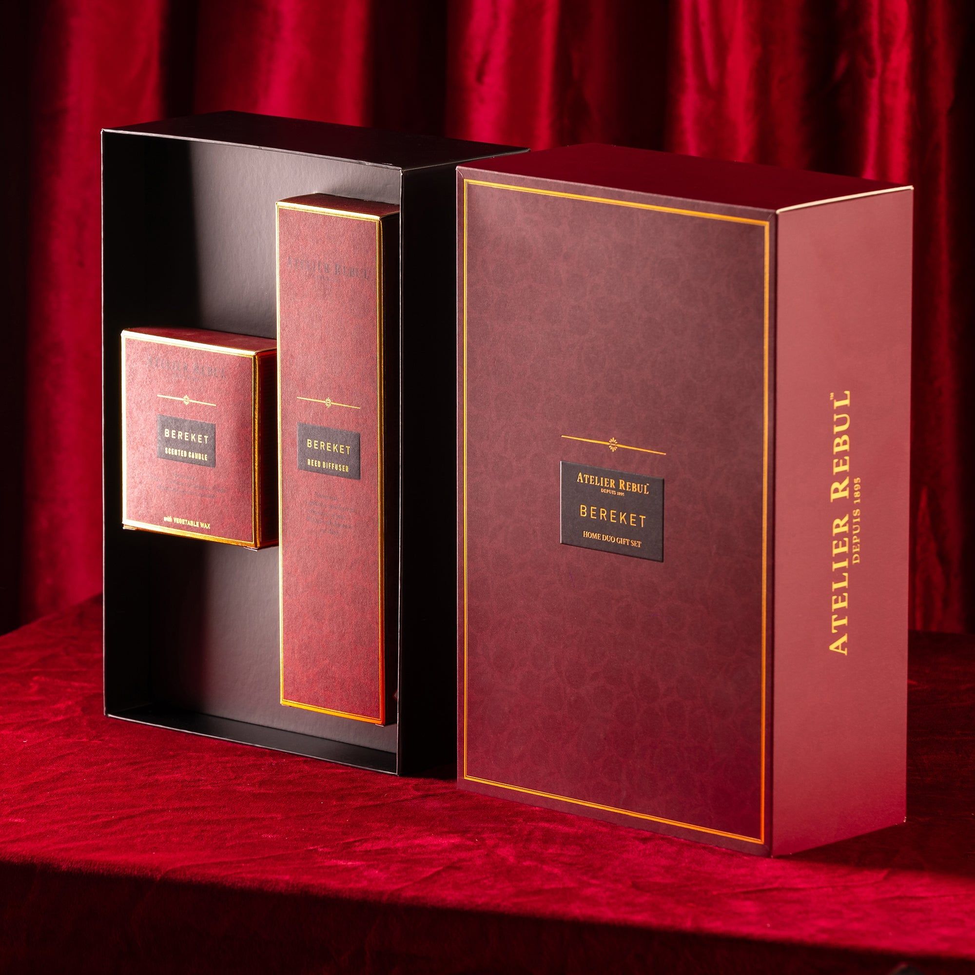 Geschenkset in offener, burgunderroter Schachtel. Enthält zwei längliche und eine quadratische Schachtel. Goldfarbene Schriftzüge.