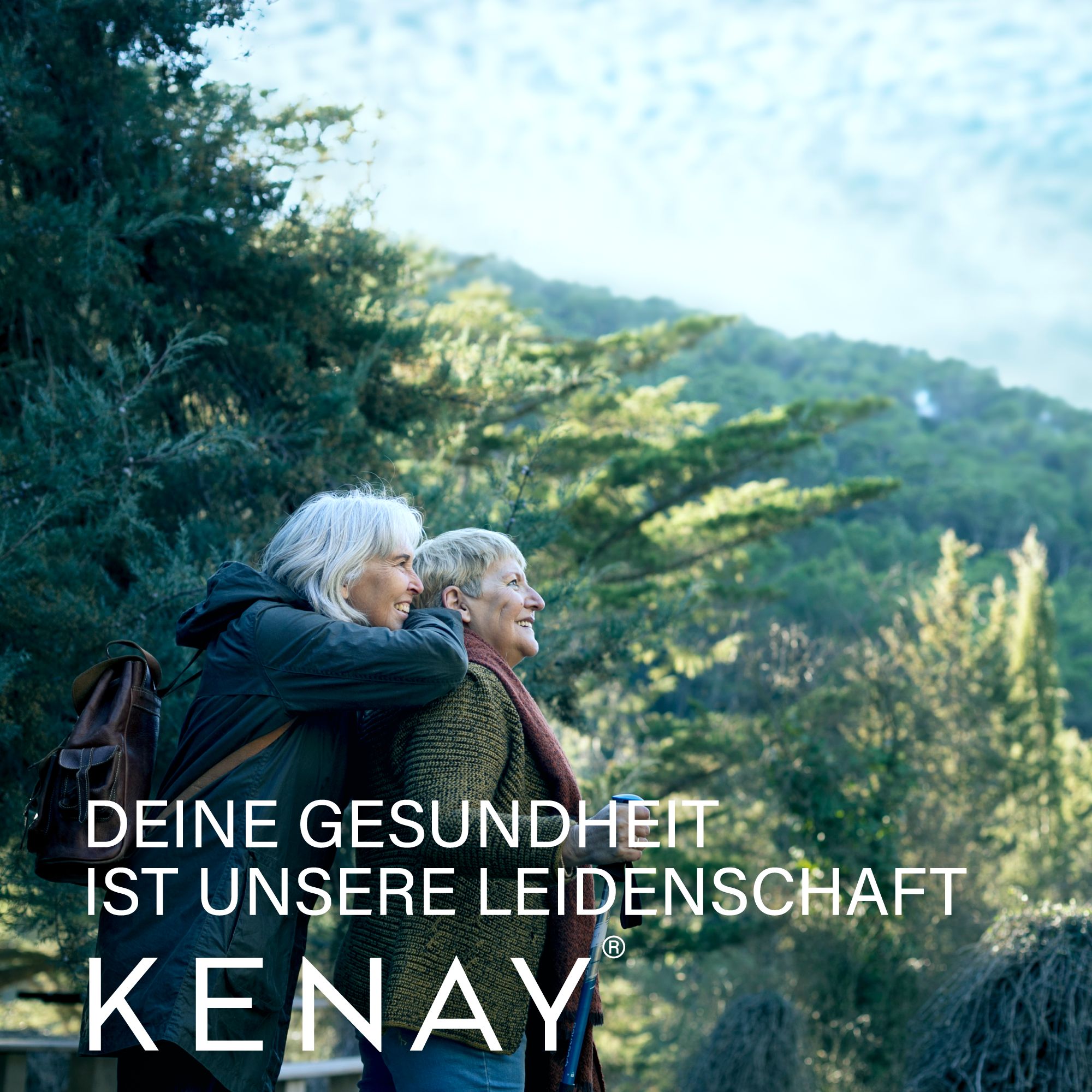 Zwei ältere Frauen im Freien, eine umarmt die andere. Text: DEINE GESUNDHEIT IST UNSERE LEIDENSCHAFT. Marke: KENAY.