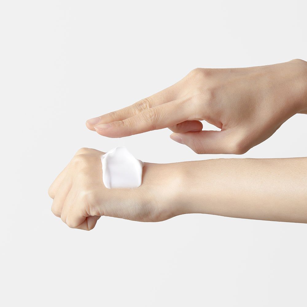 Hände mit Creme. Eine Hand trägt Creme auf. Weiße Creme auf der Haut.