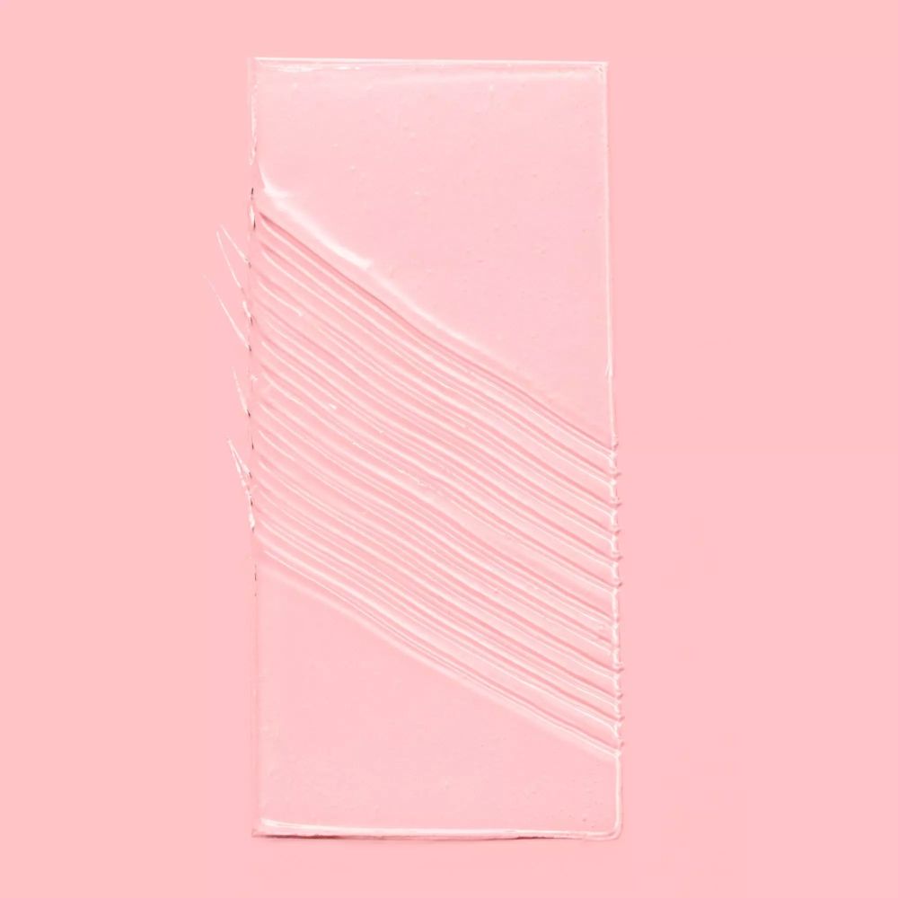 Transparente Gelspur auf rosa Hintergrund. Geformt wie ein Rechteck mit parallelen Linien.
