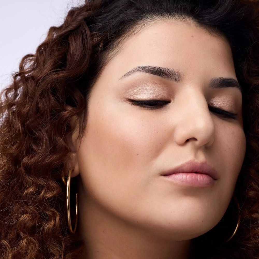 Frau mit lockigem Haar und geschlossenen Augen. Aufgetragenes Augen-Make-up.