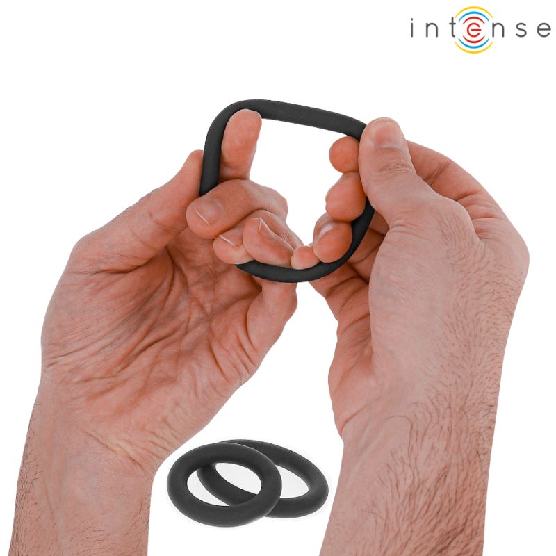 Hände halten einen schwarzen Penisring. Zwei weitere Ringe liegen darunter. Das Logo "Intense" ist oben rechts.