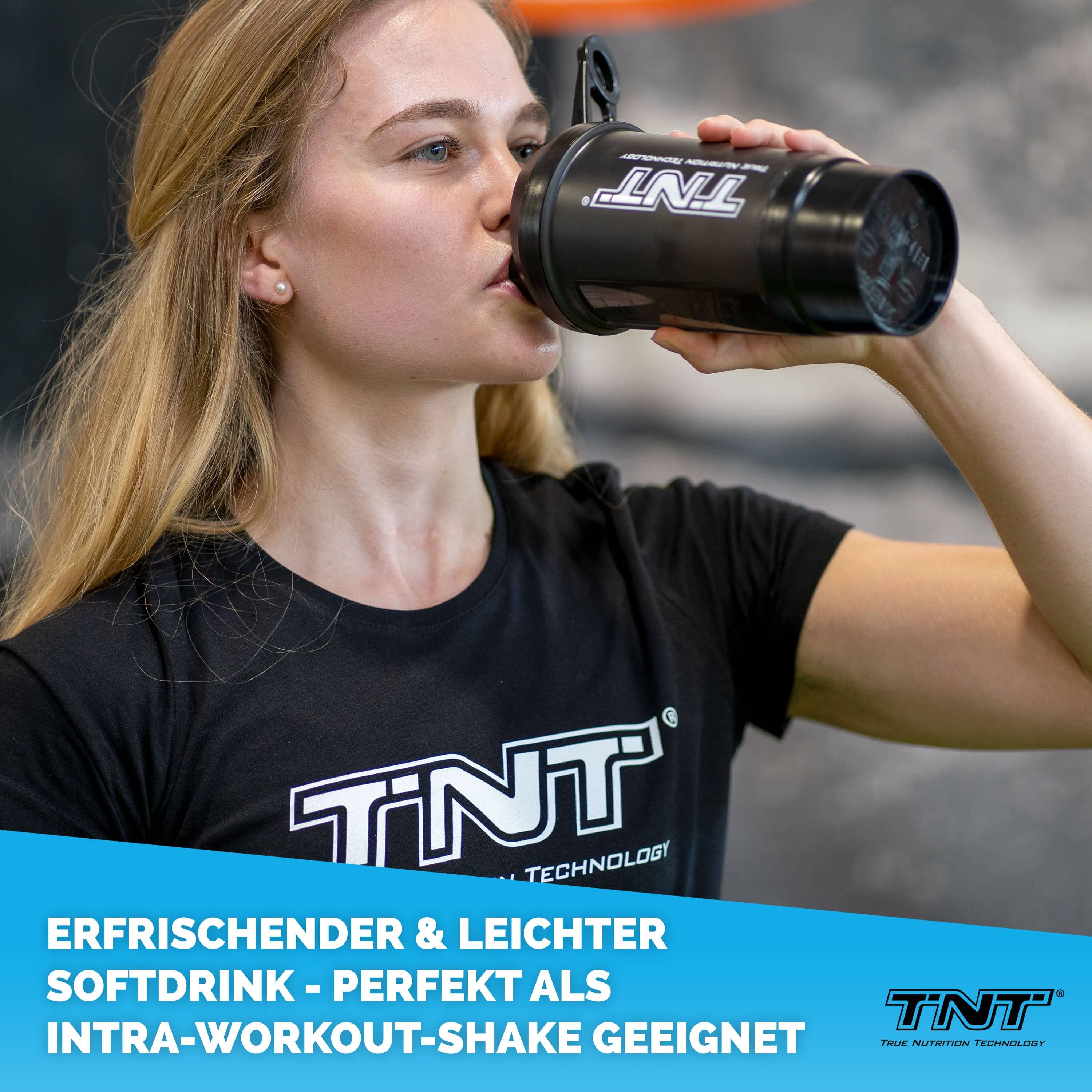 Frau trinkt aus schwarzem Shaker mit TNT-Logo. Text: Erfrischender & leichter Softdrink - perfekt als Intra-Workout-Shake geeignet.