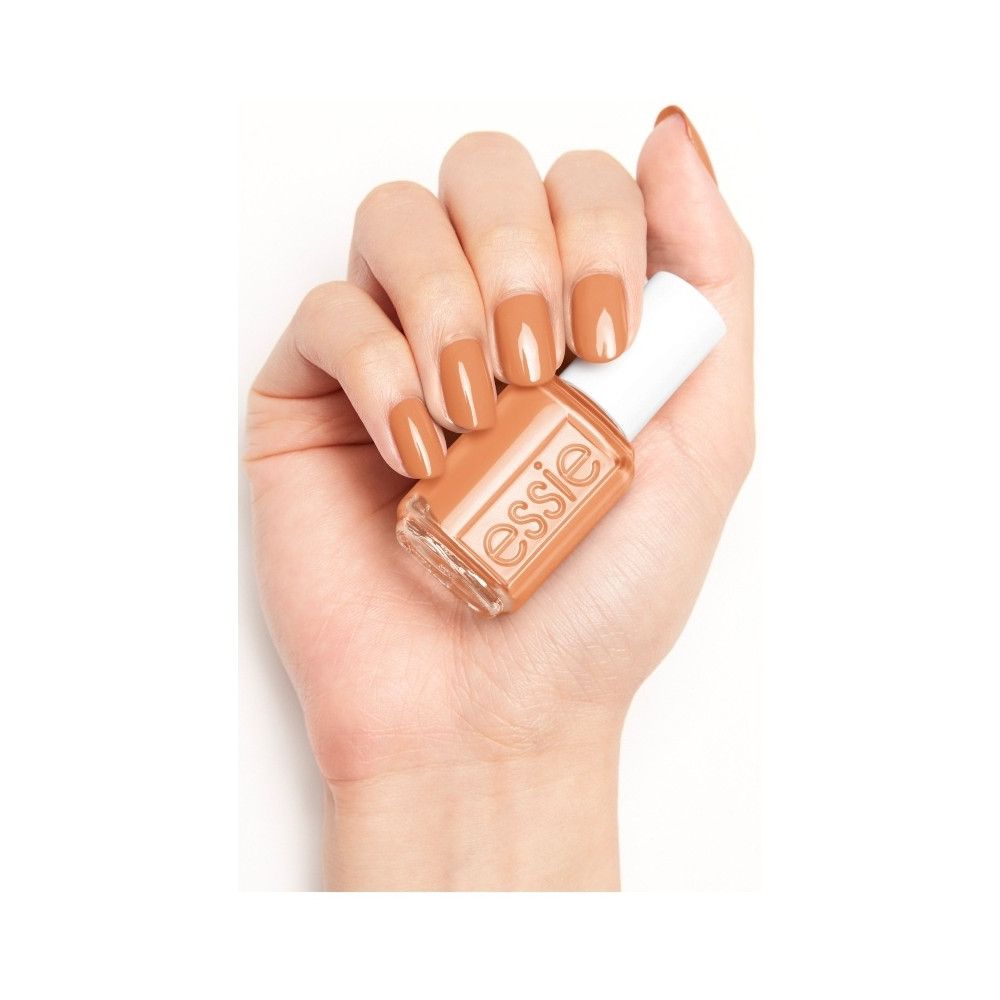 Hand hält Nagellackflasche. Nägel lackiert. Farbton: Braun-Beige. Aufschrift 'essie'.