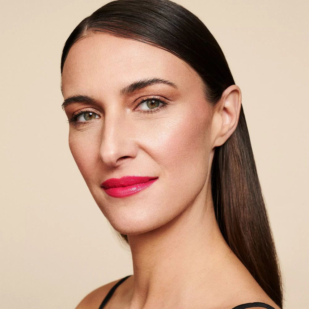 Porträt einer Frau mit Make-up. Sie trägt Lippenstift und Lidschatten. Ihr Haar ist zurückgekämmt.