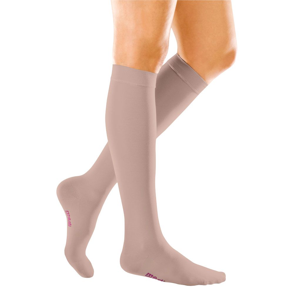 Hautfarbene Kompressionsstrümpfe am Bein. Rosa Schriftzug am Fuß. Strümpfe reichen bis zum Knie.