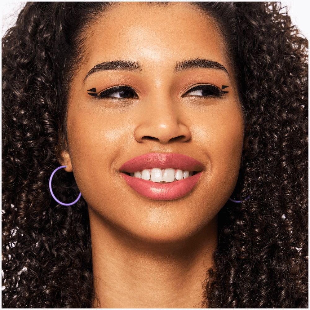 Porträt einer Frau mit rosa Lippenstiftstift. Sie trägt lilafarbene Ohrringe.