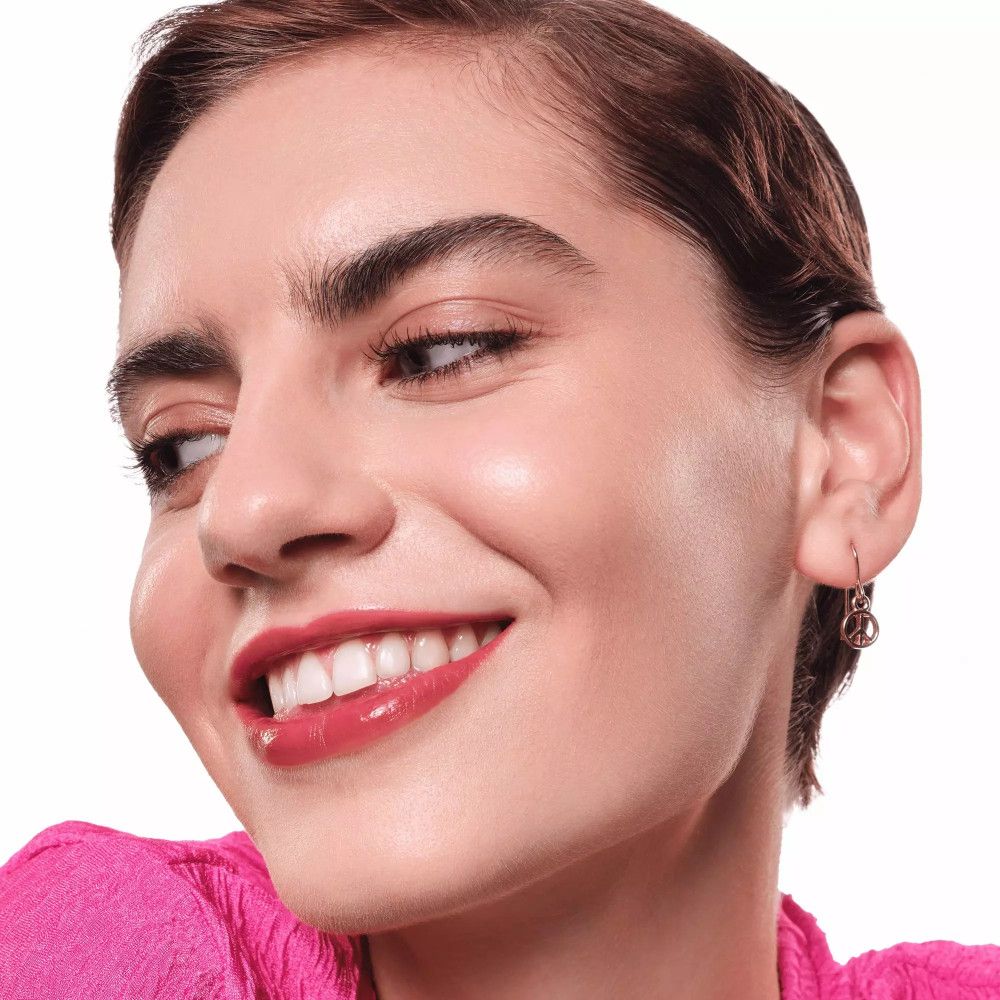 Nahaufnahme einer Frau mit Essence Hydra Kiss Lippen-Tint. Sie lächelt, trägt Ohrringe.