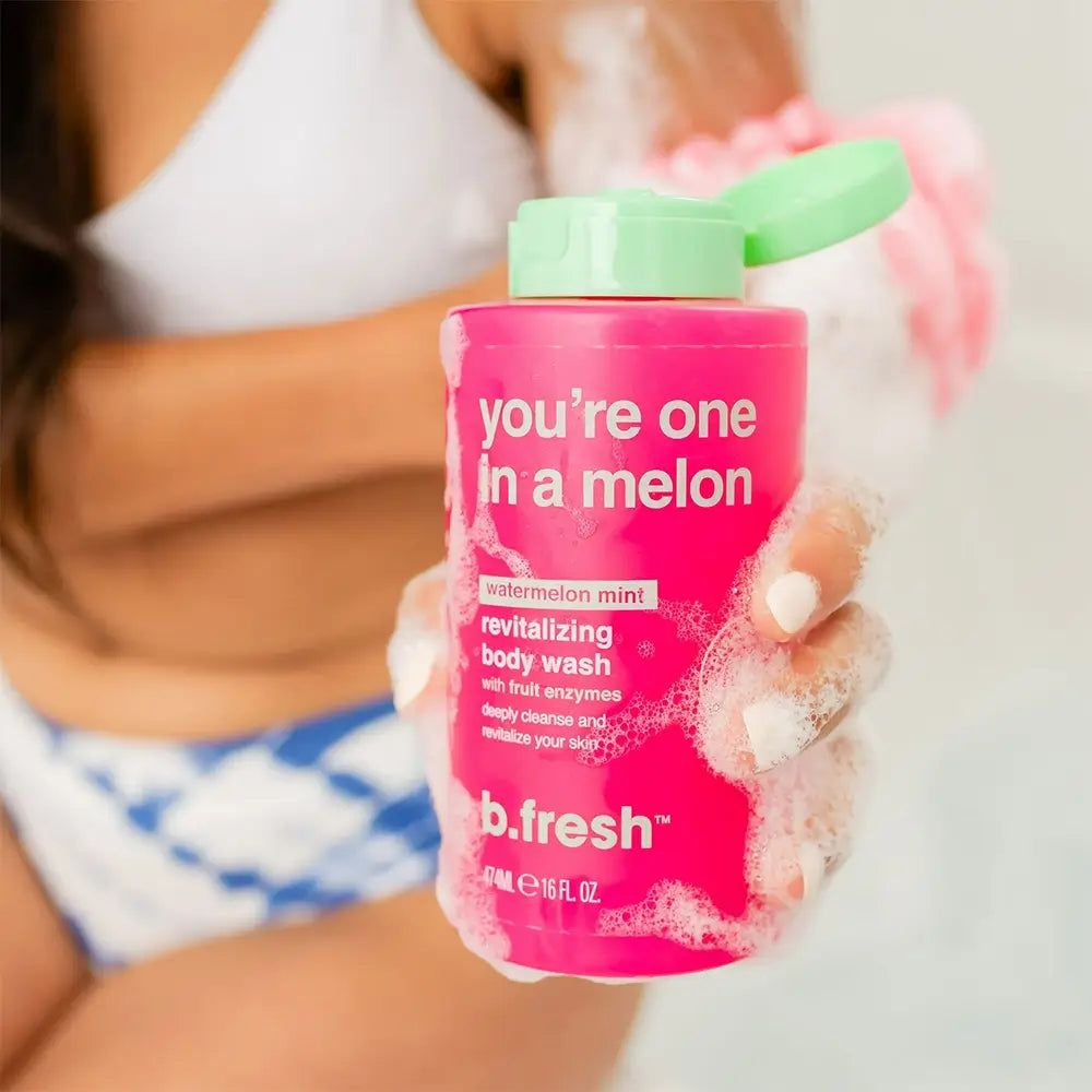 Rosa Duschgelflasche mit grünem Deckel. Aufschrift: "you're one in a melon". Produktname: b.fresh. Person hält Flasche und Waschlappen.