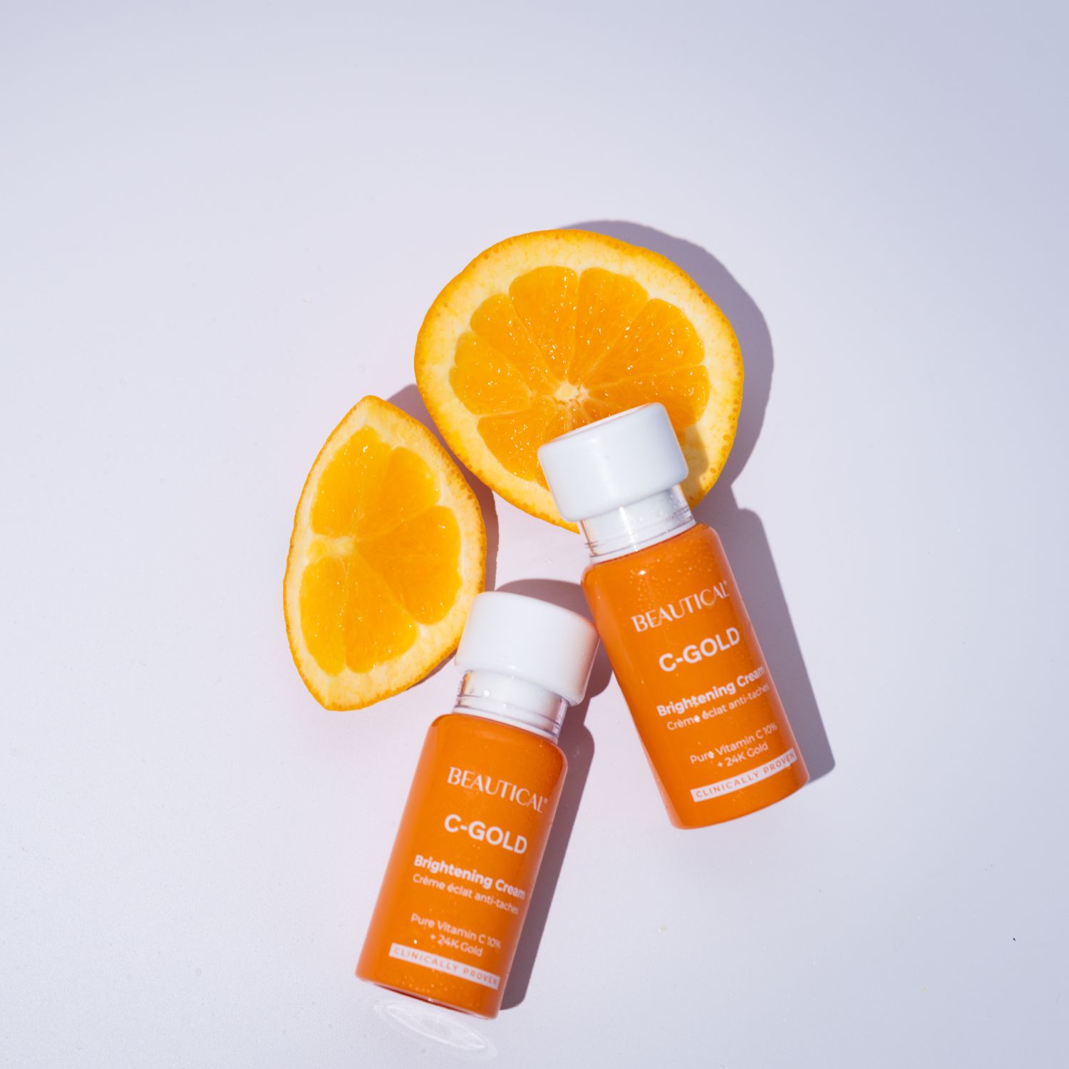 Zwei Flaschen BEAUTICAL C-GOLD Aufhellende Creme mit Orangenstücken. Orangefarbene Flaschen mit weißem Deckel.