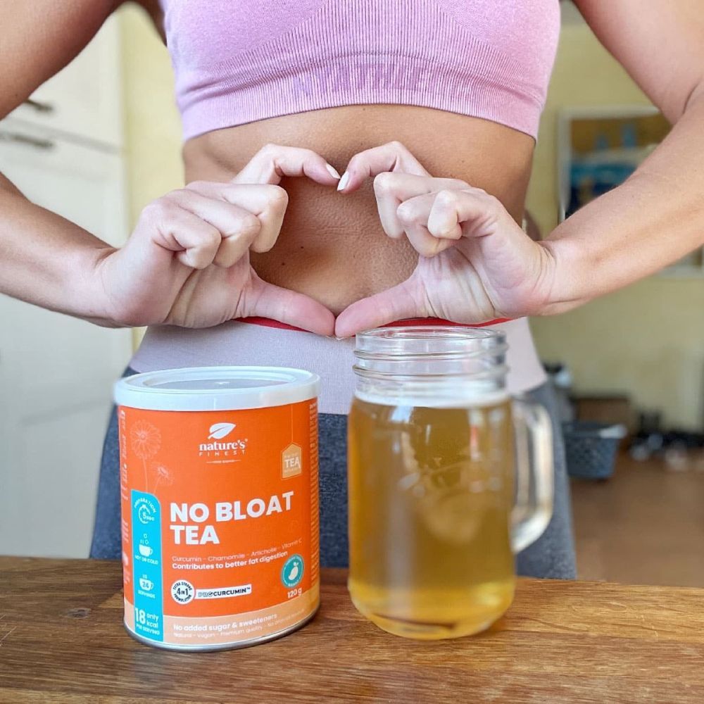 Frau formt Herz mit Händen über Bauch. Dose "NO BLOAT TEA" und Glas Tee daneben. Logo "Nature's Finest".