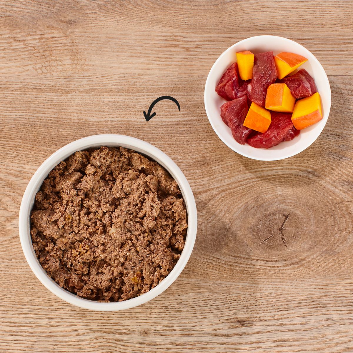 Zwei Schalen mit Hundefutter. Eine Schale mit Lamm & Kürbis, die andere mit Nassfutter. Auf Holzhintergrund.