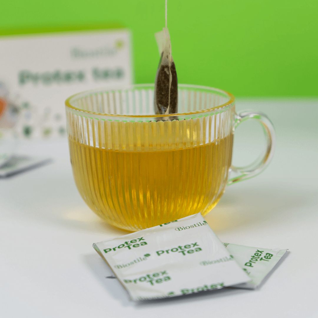 Eine Teetasse mit Biostile Protex Tee, ein Teebeutel hängt heraus, zwei einzelne Beutel liegen daneben.