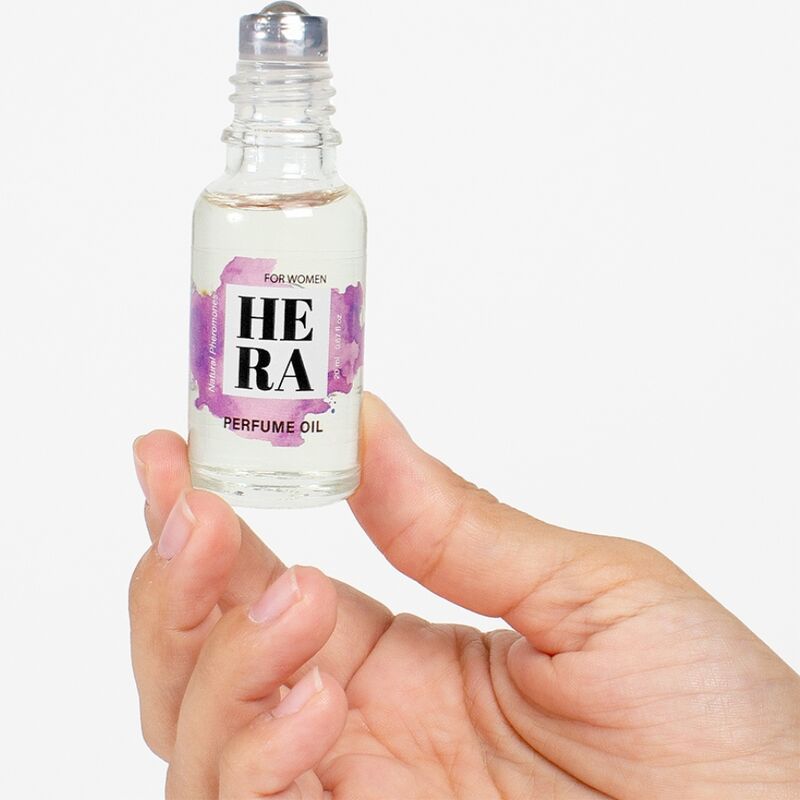 Hera Parfümöl-Flasche mit Roll-on-Applikator, gehalten in einer Hand. Lila Akzente auf dem Etikett. Transparente Flüssigkeit.