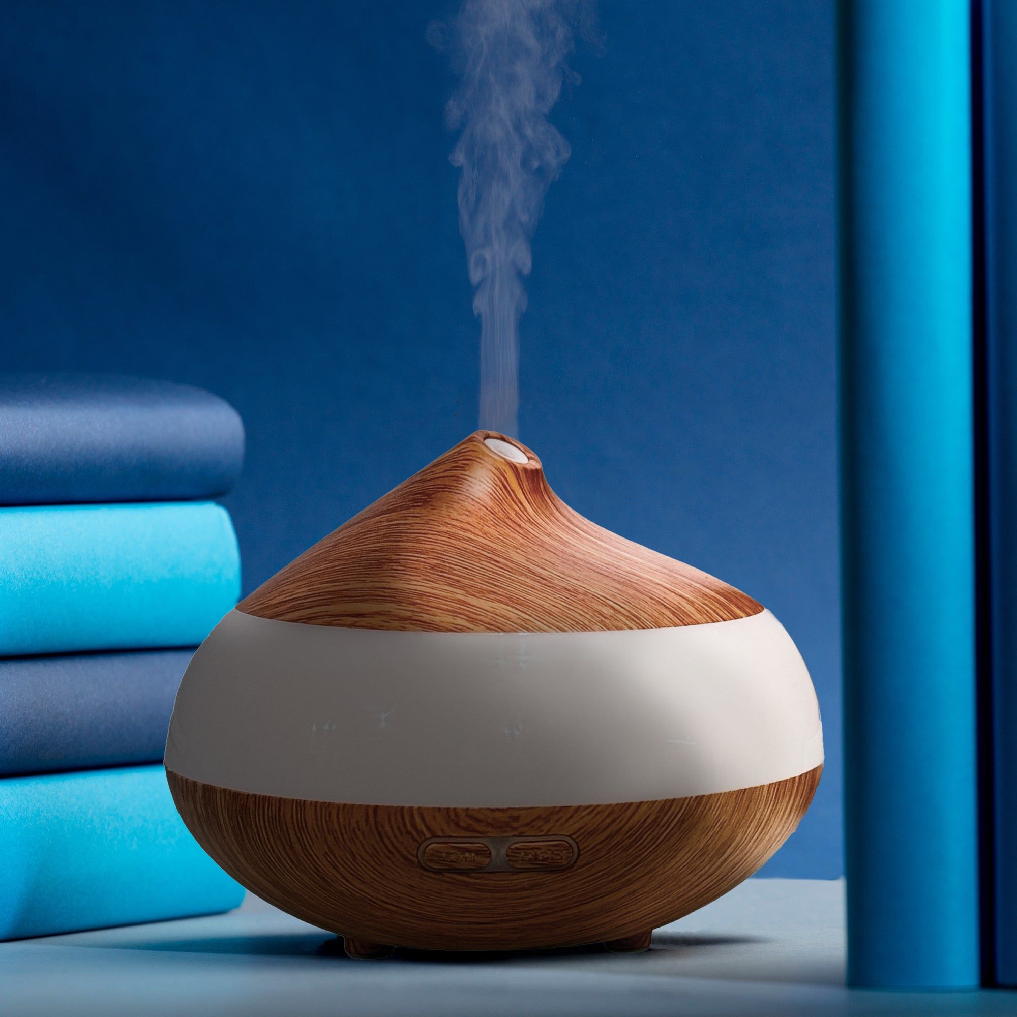 Aromadiffusor aus Holz mit weißem Band. Dampf steigt auf. Blaue Hintergründe.