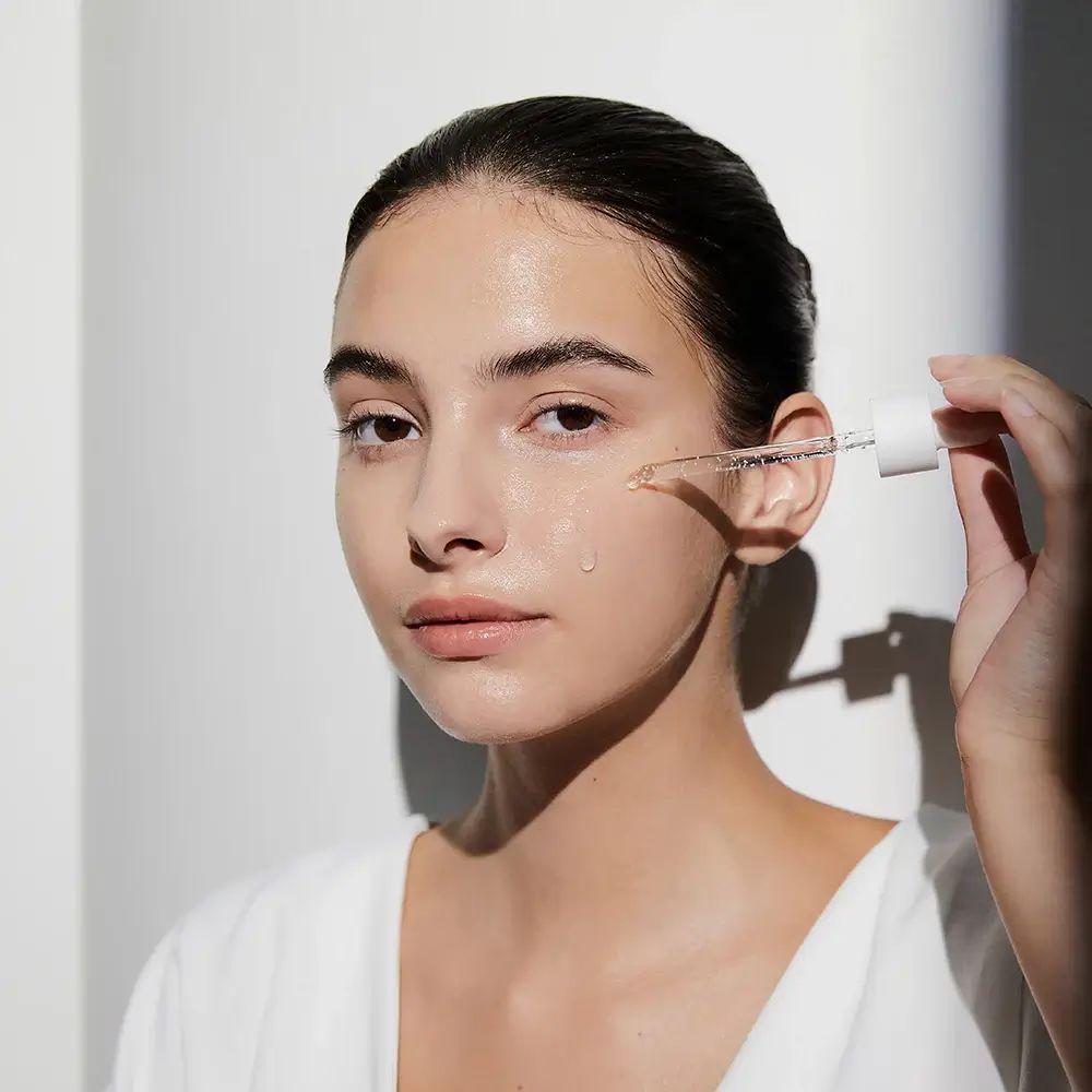 Frau mit Hautpflegeprodukt. Pipette mit Flüssigkeit. Produktname nicht sichtbar.