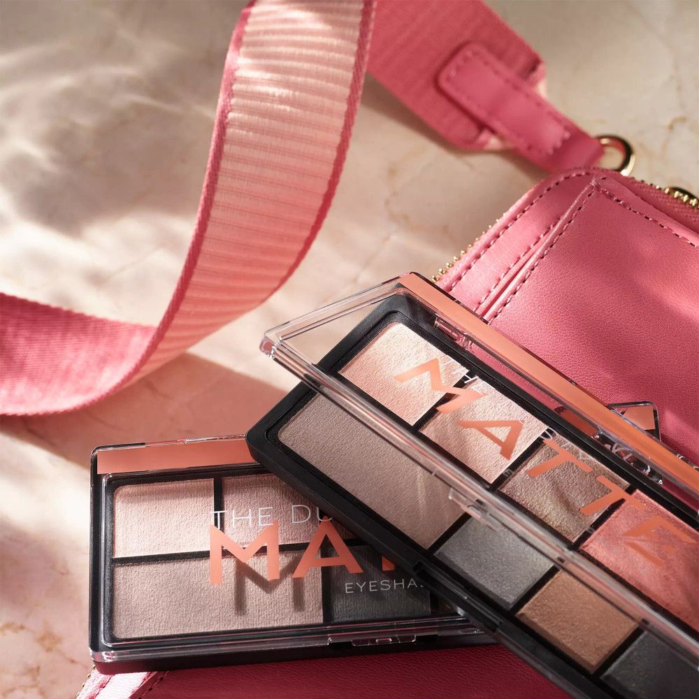 Zwei Lidschattenpaletten neben einer Handtasche. Aufschrift: MATTE. Farben: Rosa, Grau, Braun, Grün.