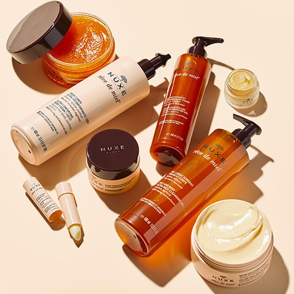 Verschiedene NUXE Rêve de Miel Produkte. Flaschen, Tiegel und Lippenbalsam. Beige und braune Verpackungen.