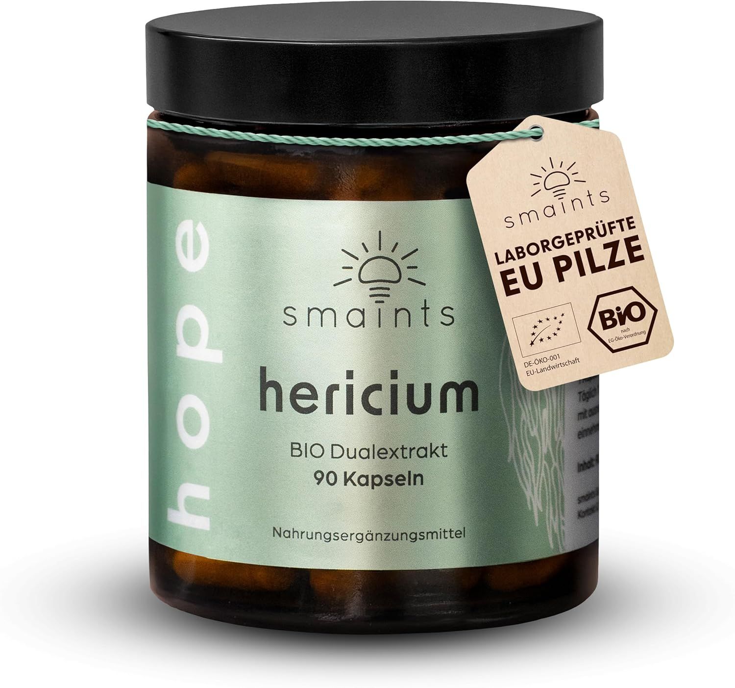Braune Glasflasche mit smaints® Hericium Kapseln. Etikett mit Produktinformationen und Bio-Siegel. Anhänger mit EU-Pilze.