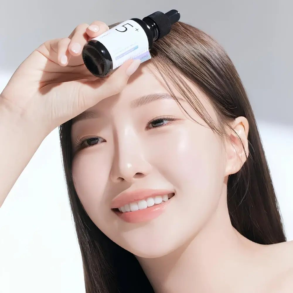 Frau hält eine schwarze Flasche mit Pipette. Aufkleber mit Text: Vitamin Concentrated Serum, Glutathione. Aufschrift: 5+.