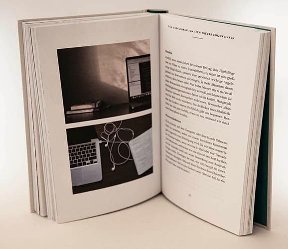 Offenes Buch mit Foto von Laptop und Kopfhörern. Text auf der rechten Seite. Grüner Buchrücken.