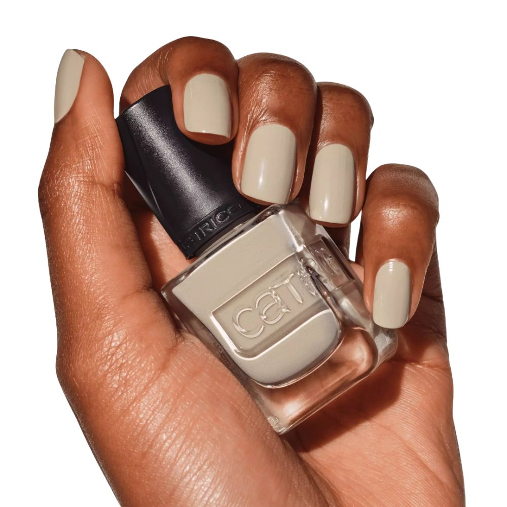 Dunkle Haut hält Nagellackflasche und lackierte Nägel. Cremefarbener Nagellack.